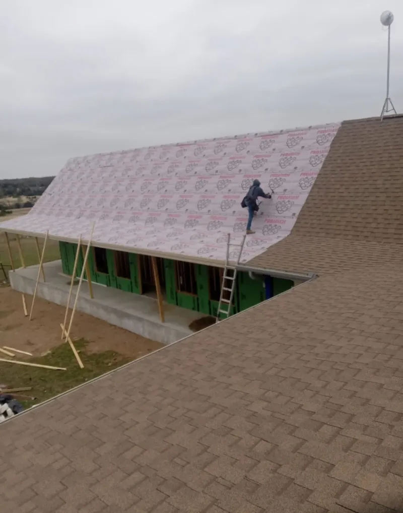 Worker preparing underlayment for a metal roof installation in Meadowbrook